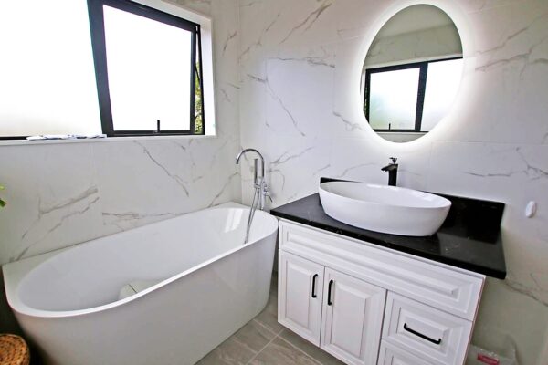 Modern bathroom with freestanding tub, vanity, and oval mirror.