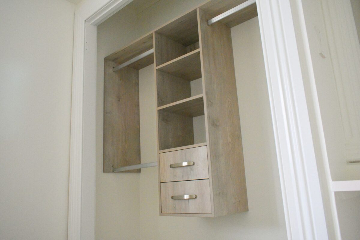 Wooden wardrobe with shelves and drawers inside a closet space.