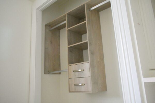 Wooden wardrobe with shelves and drawers inside a closet space.