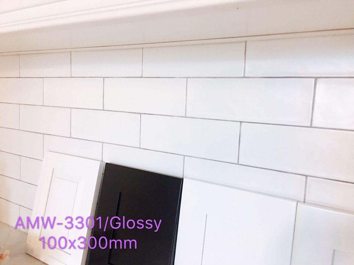 Glossy white subway tiles with black and white cabinet samples.