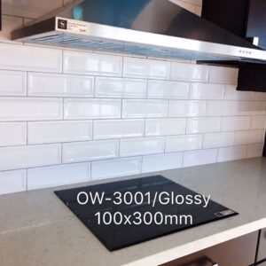 Glossy white subway tile backsplash with stovetop and range hood.