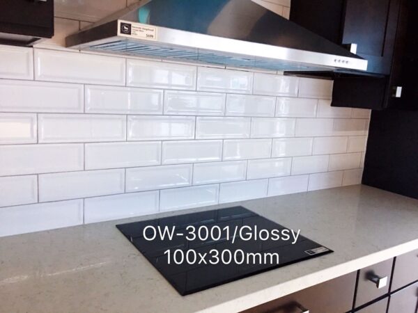 Glossy white subway tile backsplash with stovetop and range hood.