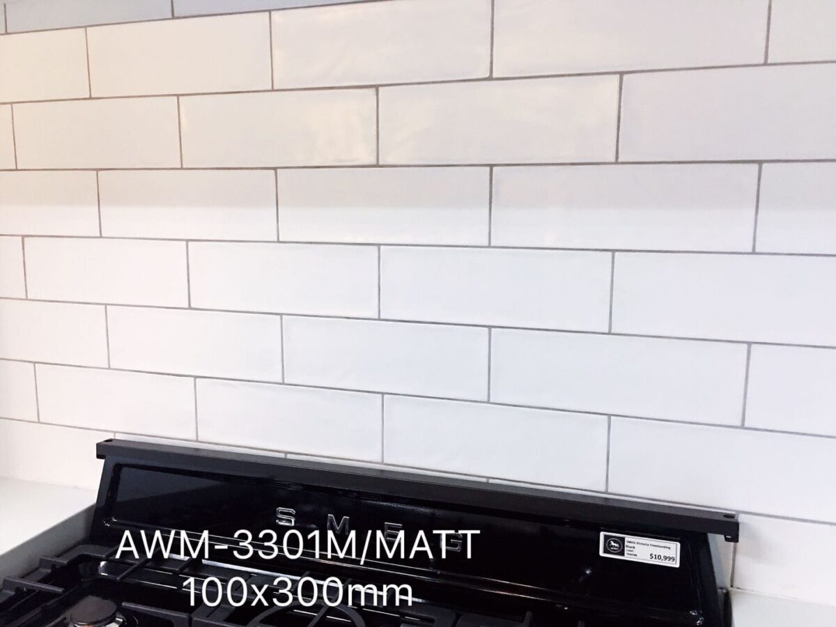 White subway tile backsplash with black stove, labeled AWM-3301M/MATT 100x300mm.
