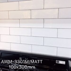 White subway tile backsplash with black stove, labeled AWM-3301M/MATT 100x300mm.