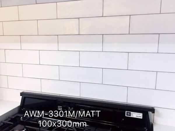 White subway tile backsplash with black stove, labeled AWM-3301M/MATT 100x300mm.