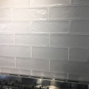 White subway tile backsplash above a stainless steel stove.