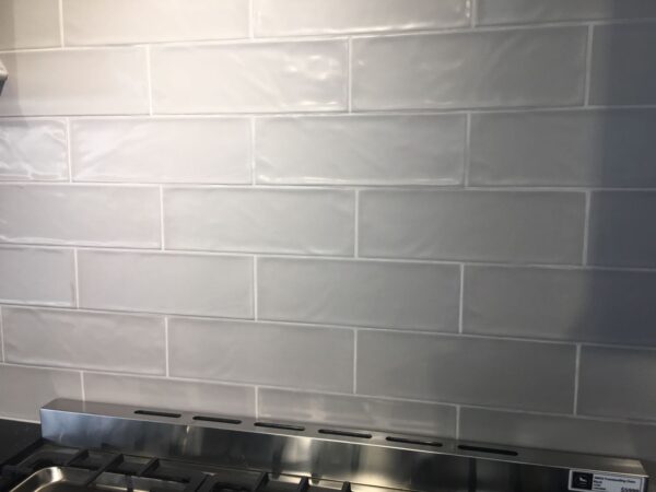 White subway tile backsplash above a stainless steel stove.