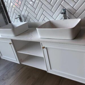 Modern bathroom vanity with double sinks and herringbone tile backsplash.