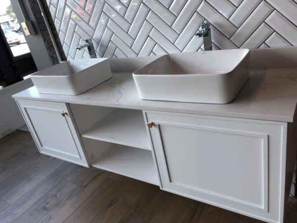 Modern bathroom vanity with double sinks and herringbone tile backsplash.