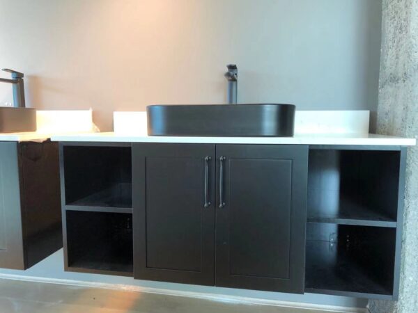 Modern black bathroom vanity with open shelves and a sleek sink.