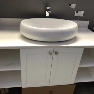 White ceramic bathroom sink on a countertop with storage cabinet.