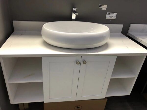 White ceramic bathroom sink on a countertop with storage cabinet.