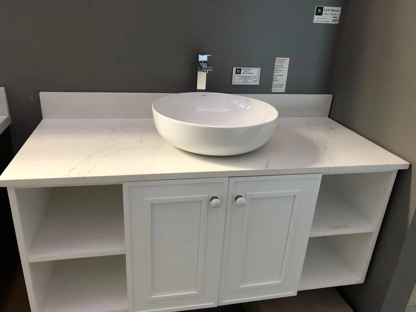 White bathroom vanity with round basin and faucet against gray wall.