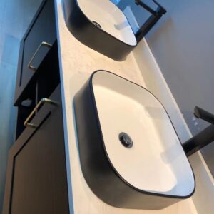 Modern black and white bathroom sinks on marble countertop.