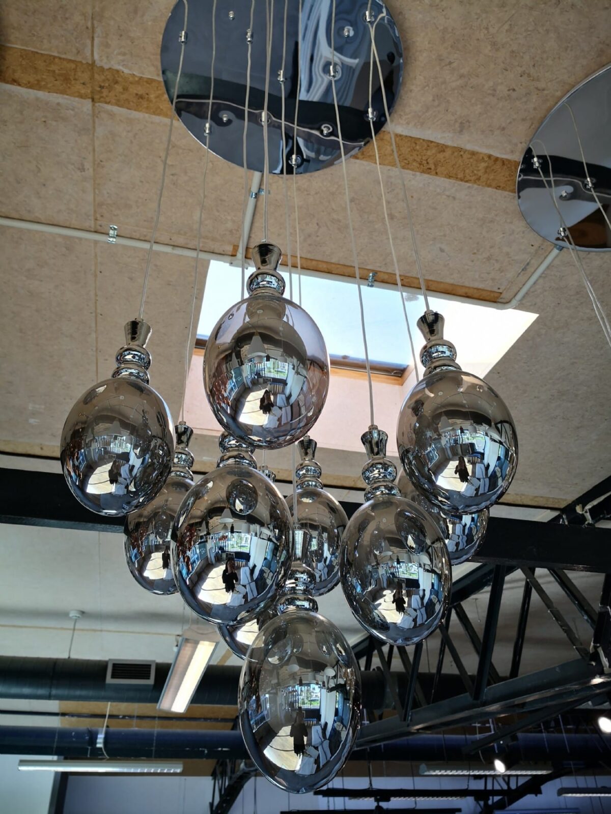 Modern chrome pendant lights hanging from the ceiling in a kitchen showroom.