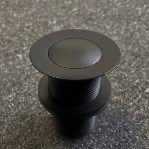 Matte black 32mm pop-up waste on textured surface.