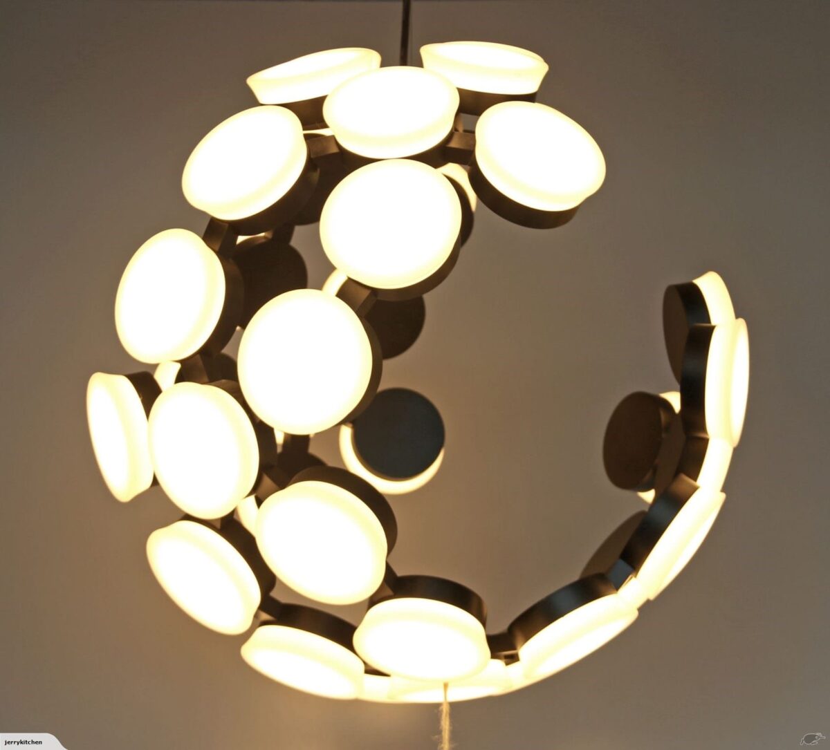 Modern circular chandelier with glowing white lights.