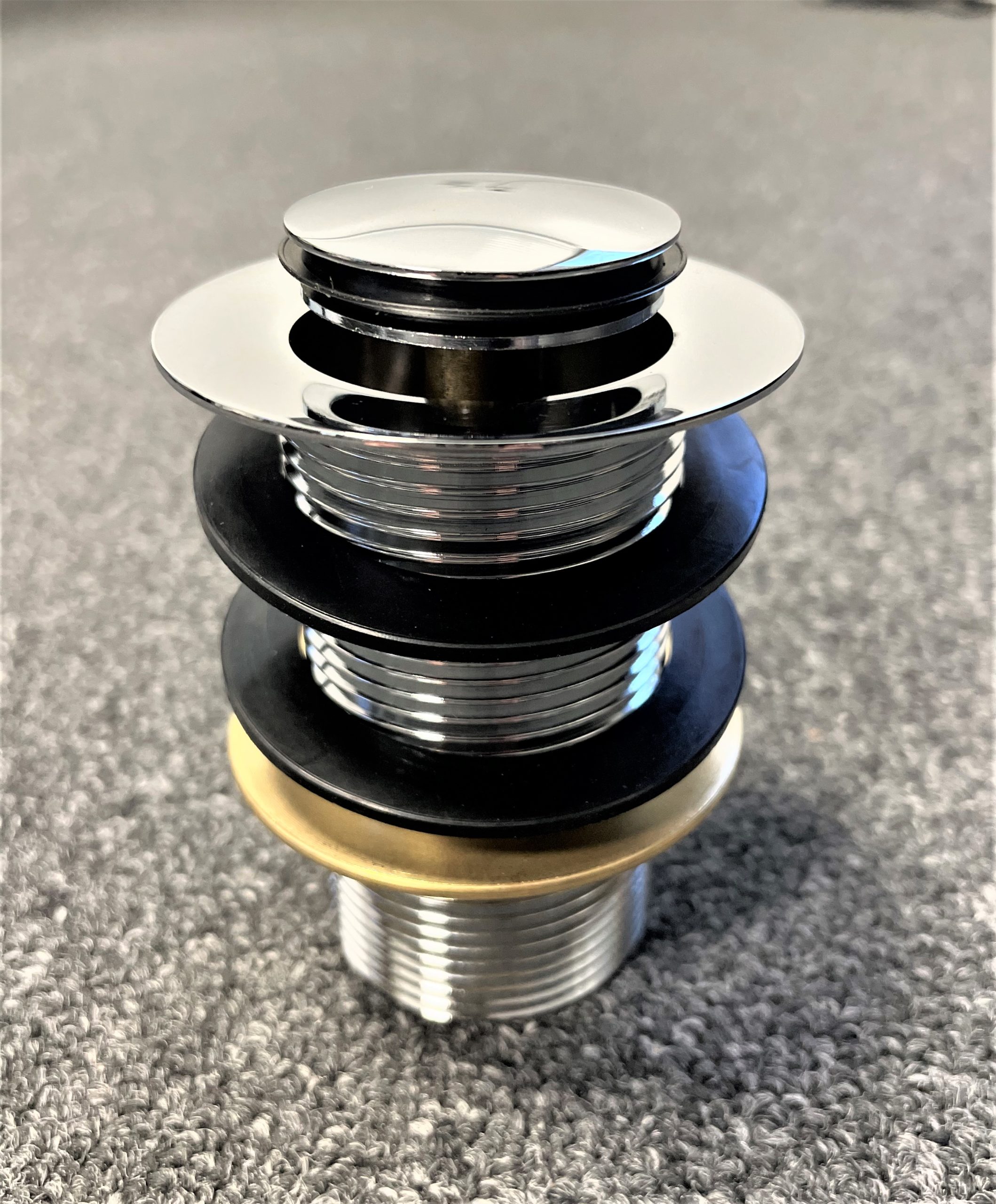 Chrome pop-up waste without overflow on carpeted surface.