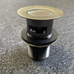 Bronze pop-up waste with overflow on carpeted floor.