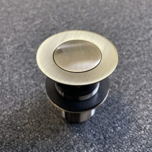 Bronze pop-up waste with overflow on textured surface.