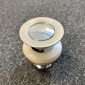 Chrome solid brass pop-up waste with overflow on gray surface.