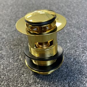 Gold pop-up waste with overflow on gray surface.