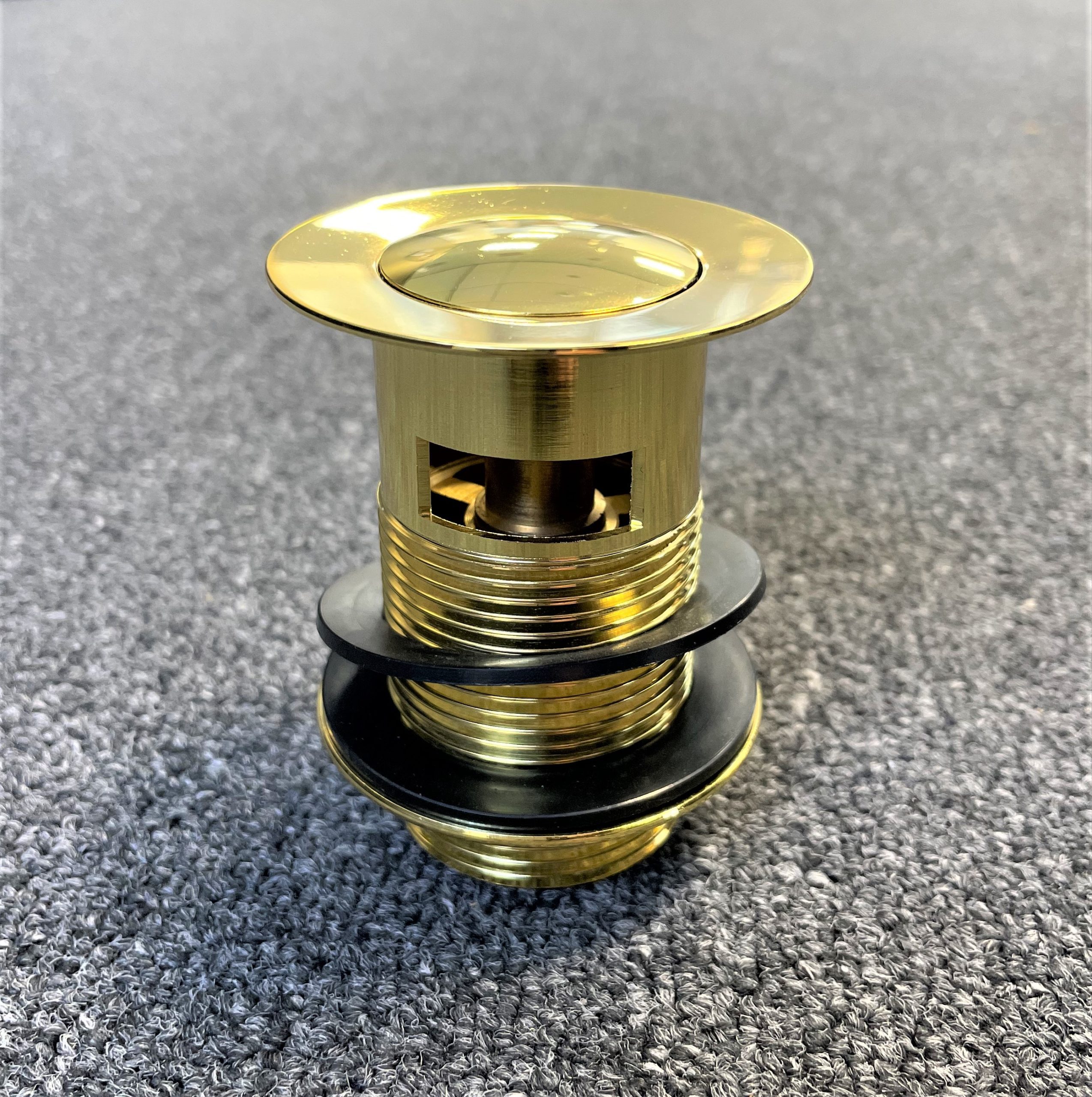 Gold pop-up waste with overflow, top view on gray surface.