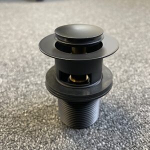 Matt black pop-up waste with overflow on carpeted floor.