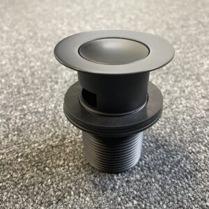 Matt black pop-up waste with overflow on gray surface.