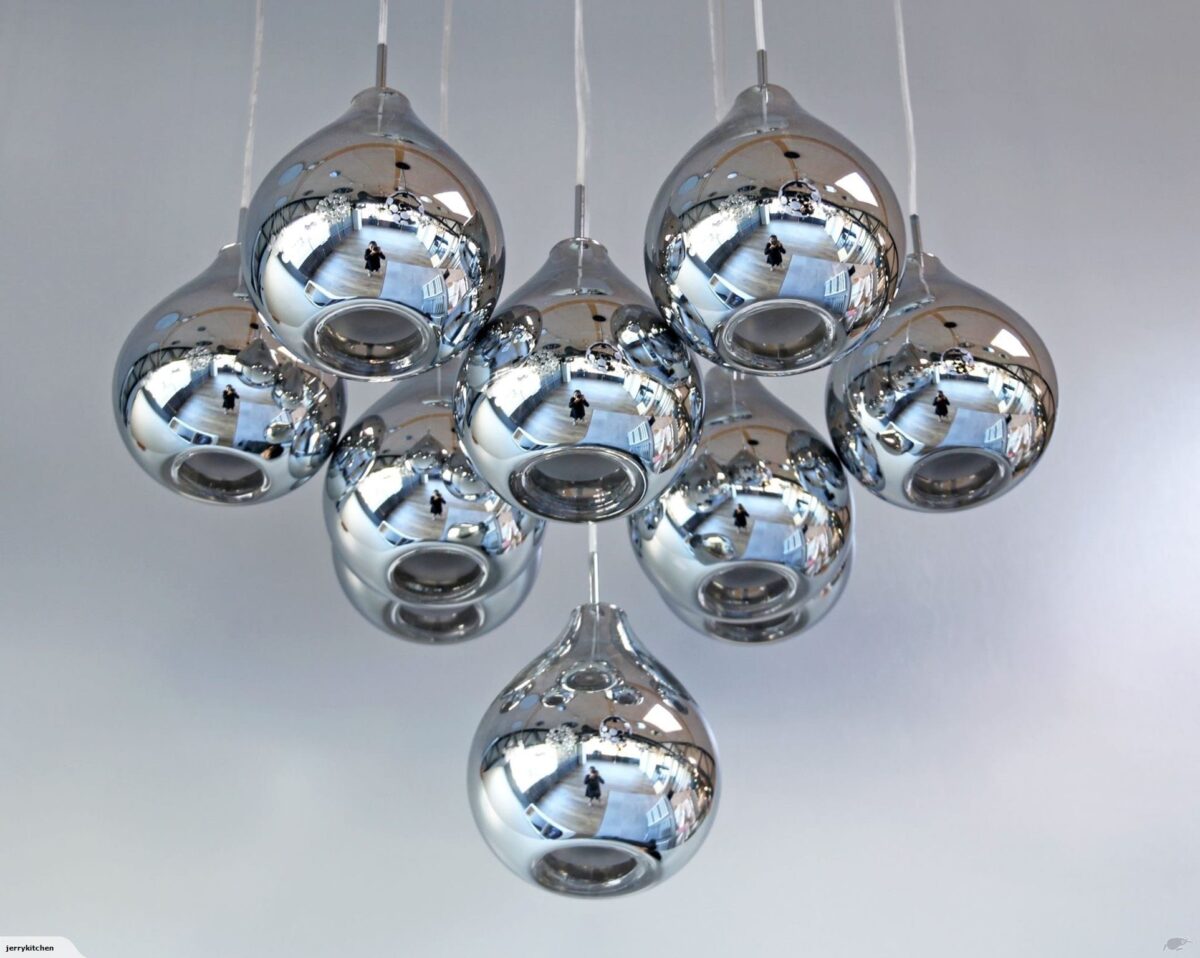 Cluster of modern chrome pendant lights against a white ceiling.