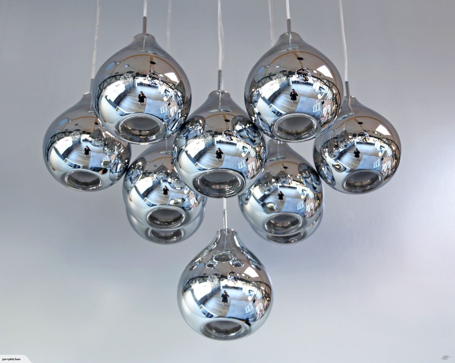 Cluster of modern chrome pendant lights against a white ceiling.