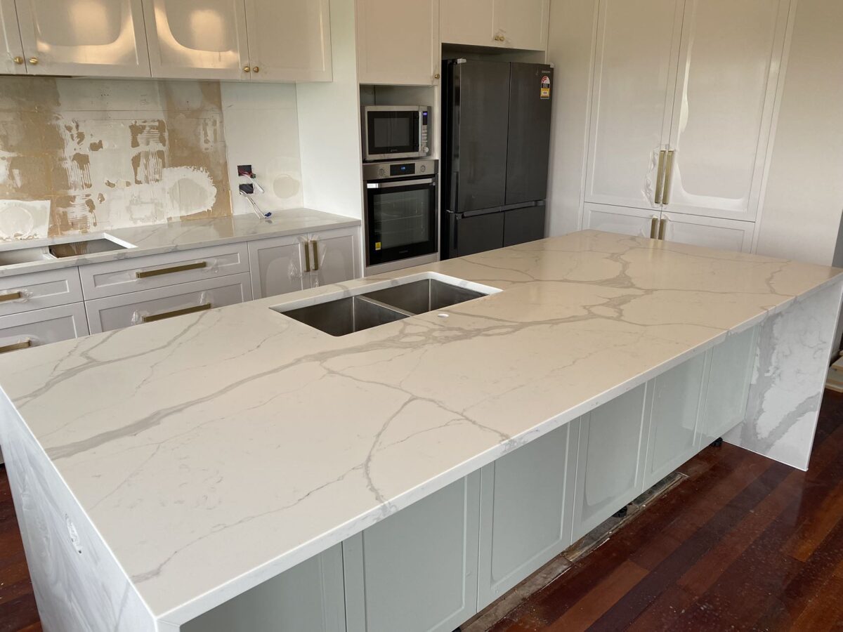 Calacatta Sky Quartz kitchen countertop with sink, surrounded by white cabinets.