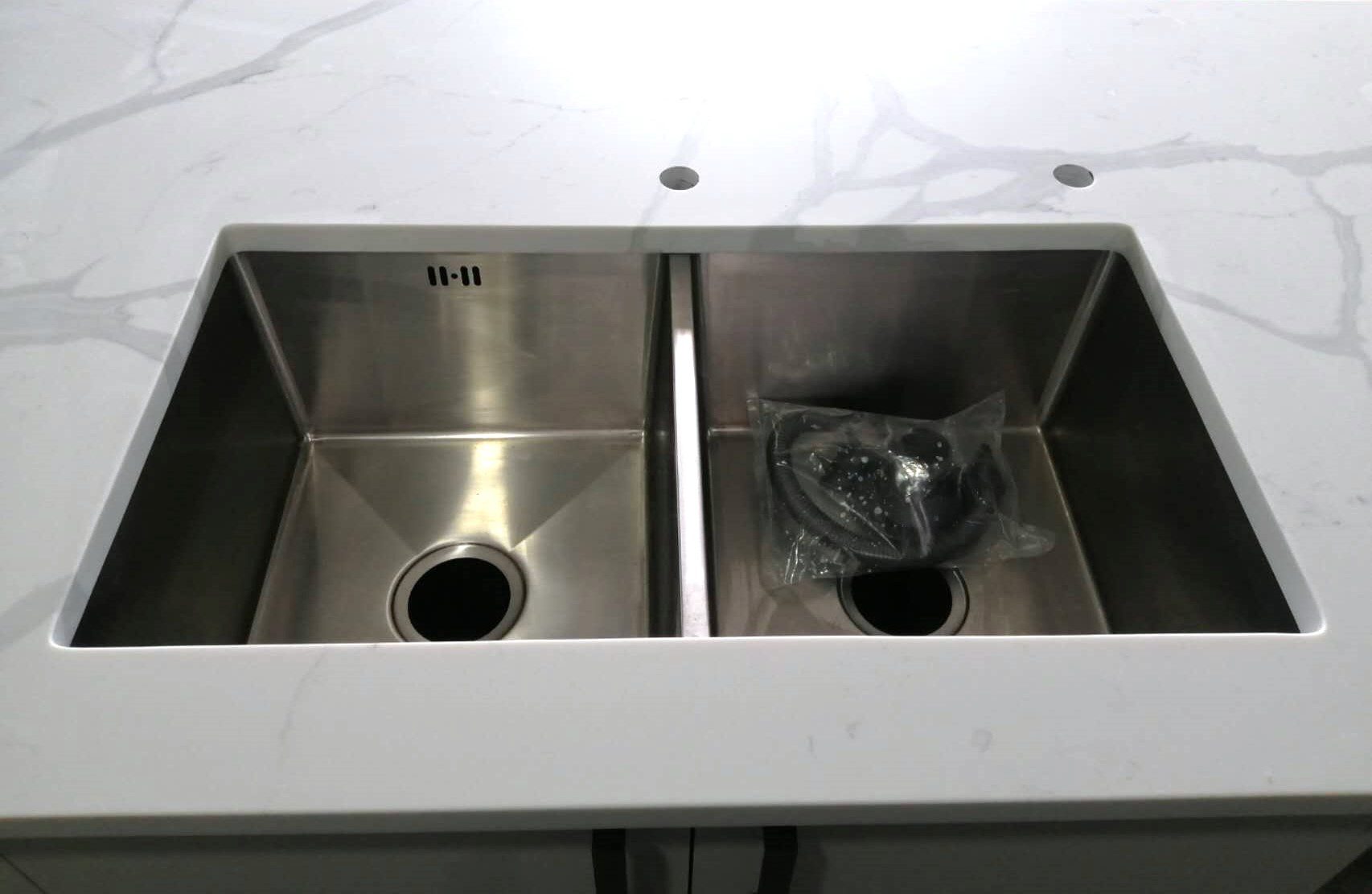 Double stainless steel sink on Calacatta Sky Quartz countertop.