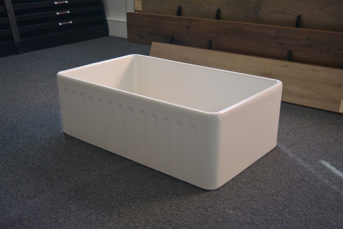 White ceramic farmhouse sink on display in showroom.