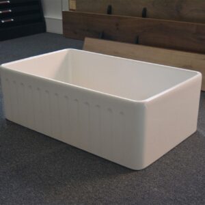 White ceramic farmhouse sink on display in showroom.