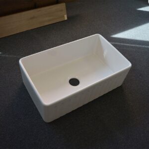 White rectangular kitchen sink on dark carpeted floor.