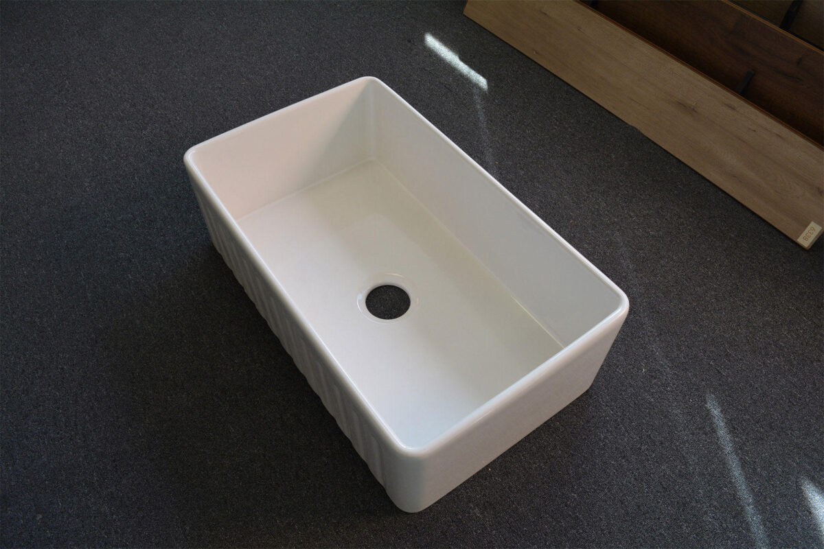 White rectangular kitchen sink on dark surface.