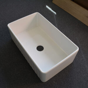 White rectangular kitchen sink on dark surface.