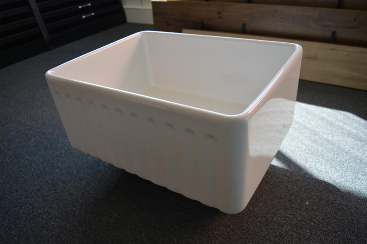 White ceramic kitchen sink on dark countertop.