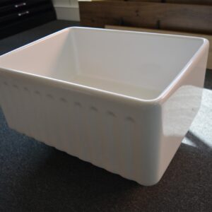 White ceramic kitchen sink on dark countertop.