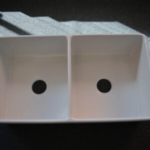 Double kitchen sink with sunlight on dark surface.