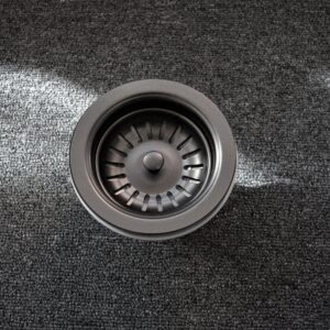 A stainless steel sink strainer on a dark carpet.