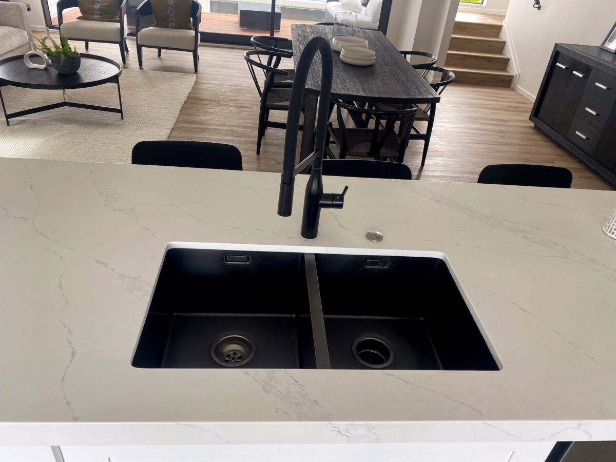 Modern kitchen sink with black faucet and marble countertop.