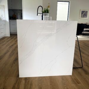 Modern kitchen with marble island and wooden flooring.