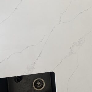White marble countertop with subtle gray veining and a black sink corner.