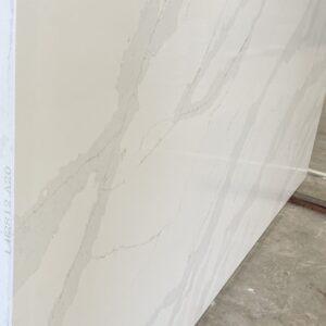 White marble slab with subtle gray veining, displayed in a showroom.