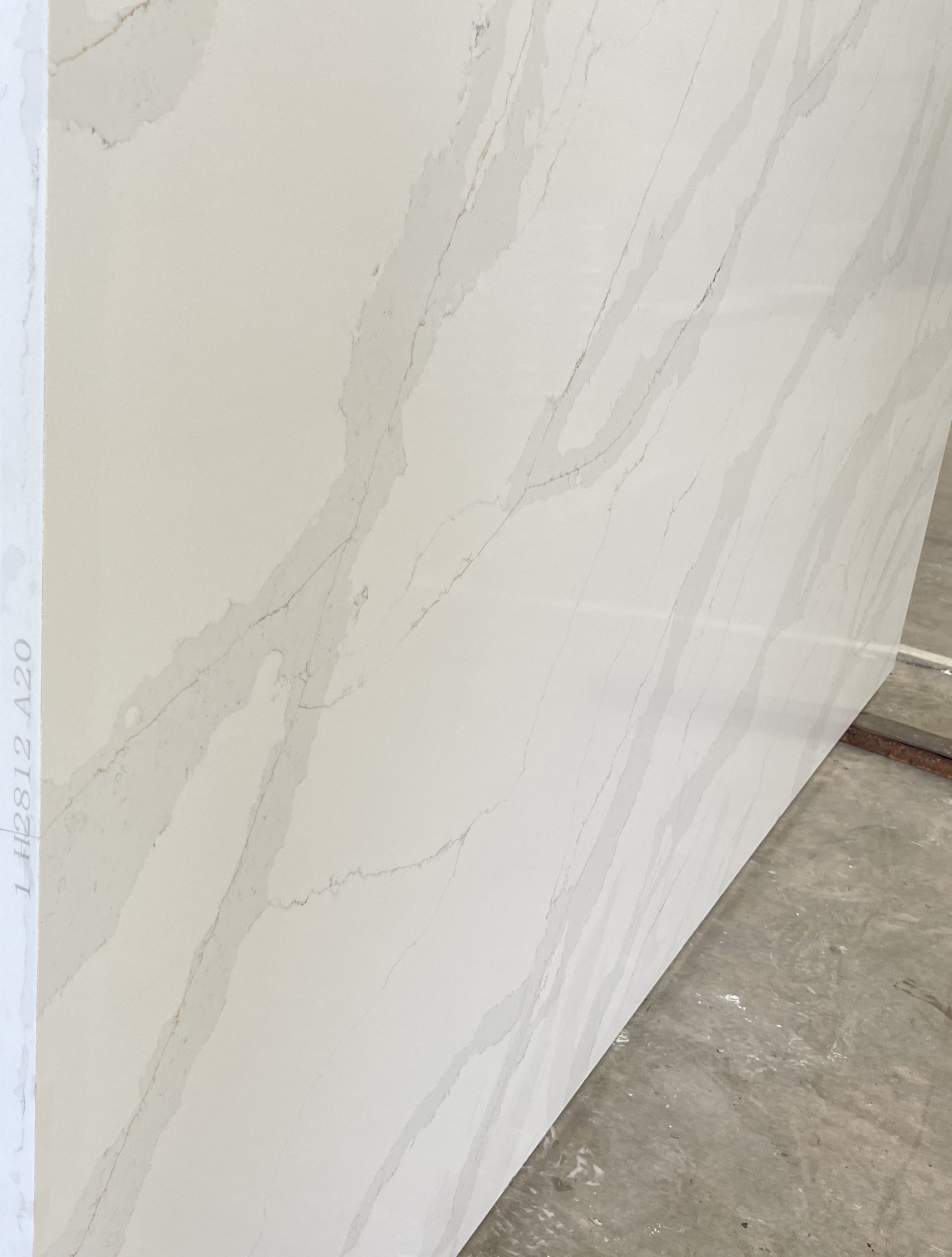 White marble slab with subtle gray veining, displayed in a showroom.
