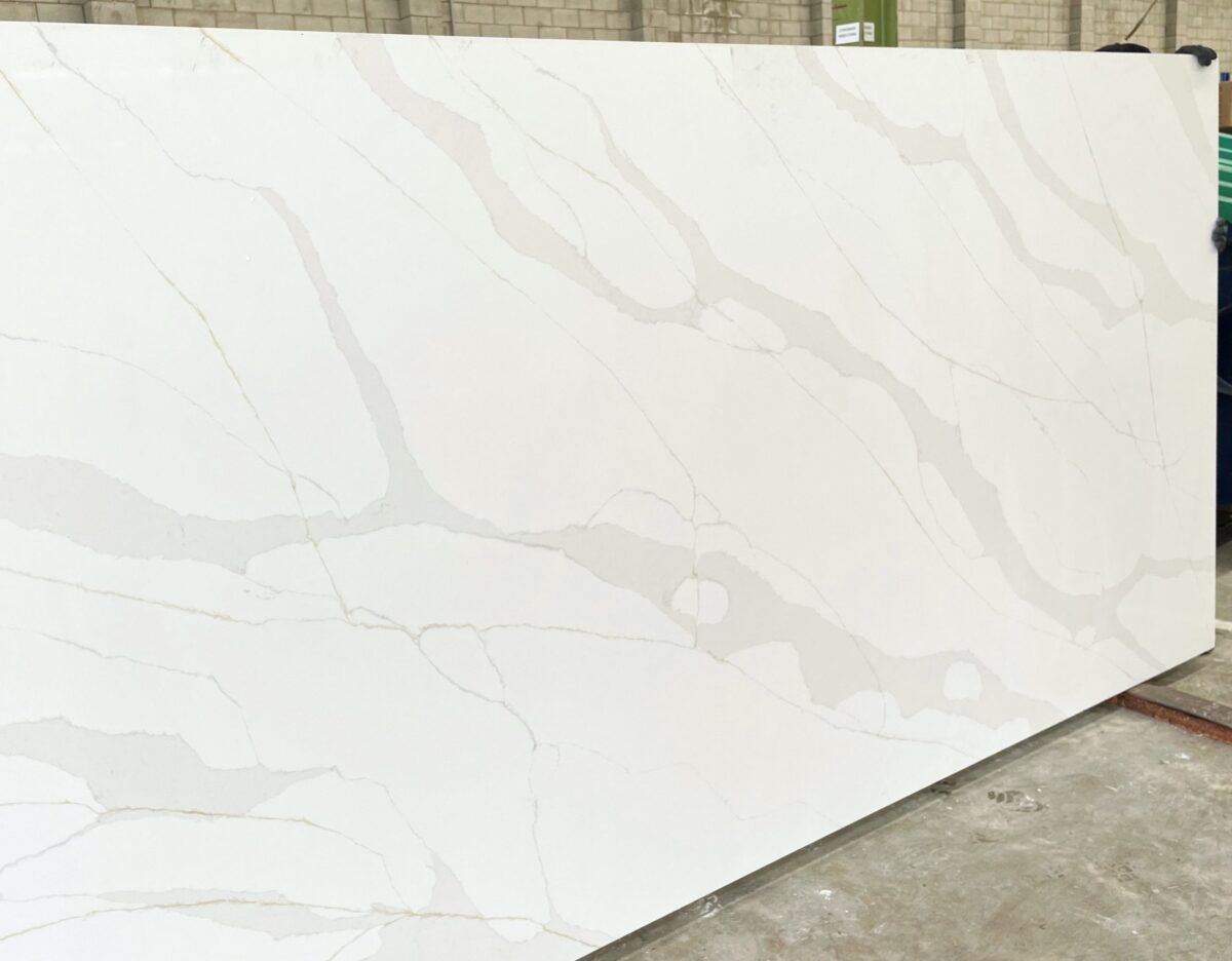 White marble slab with subtle gray veining in a warehouse setting.