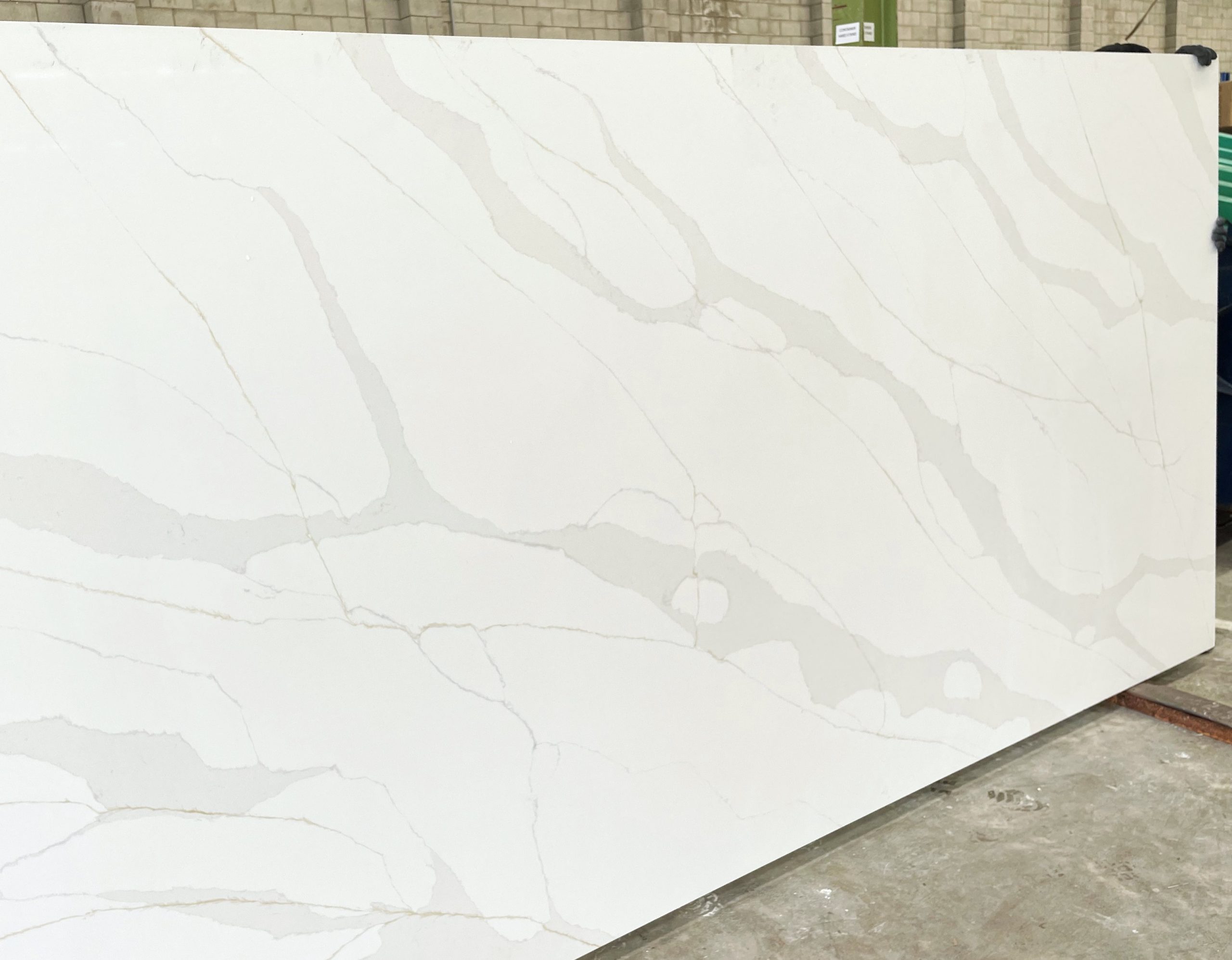 White marble slab with subtle gray veining in a warehouse setting.