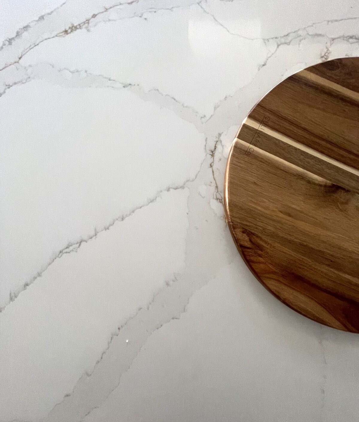 Marble countertop with wooden cutting board on Carrara Golden surface.